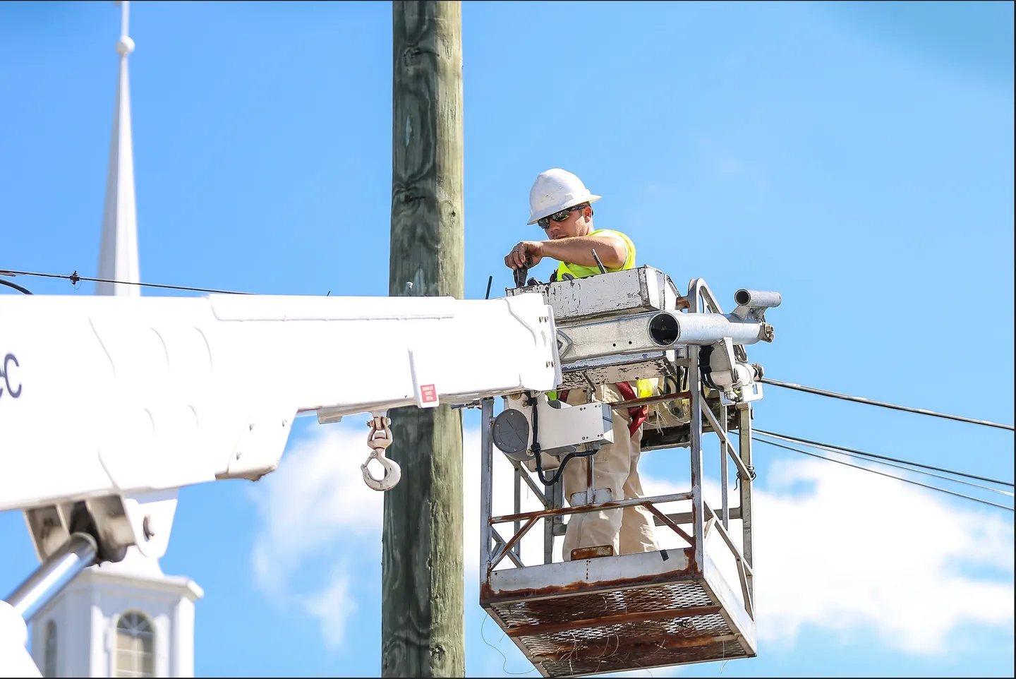 A man in a bucket is working on the power lines.