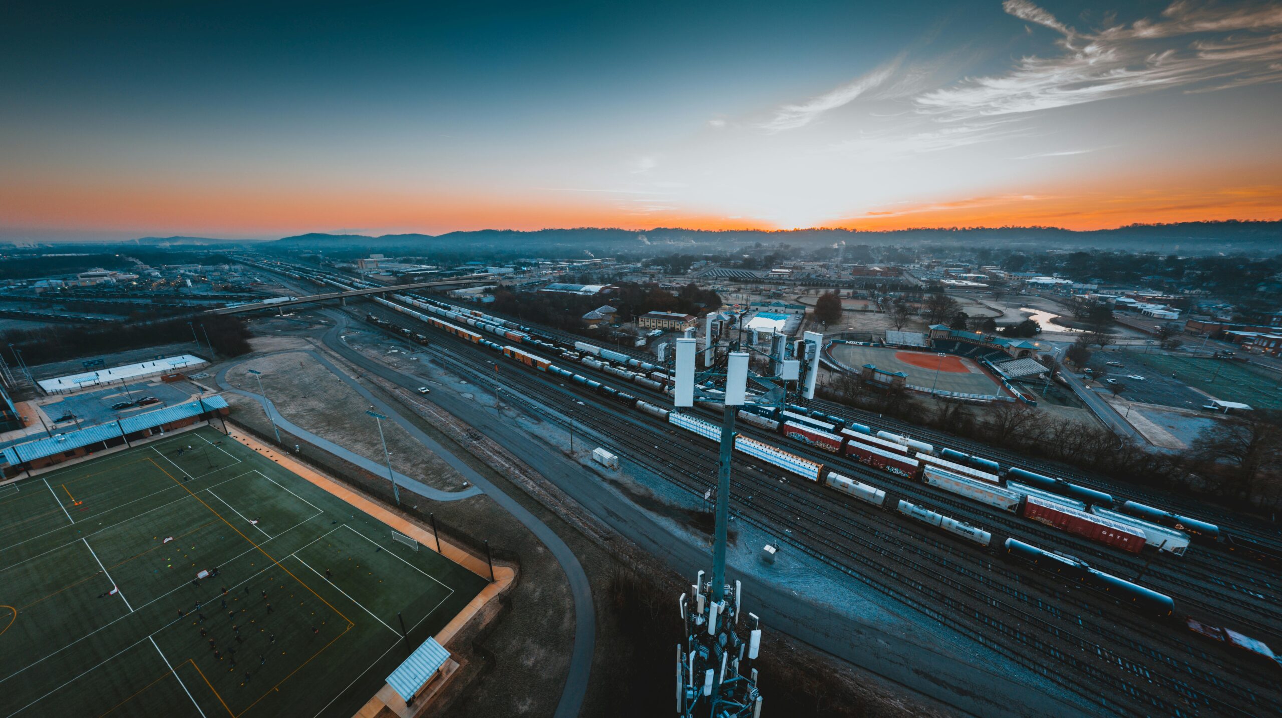 A train yard with trains on the tracks and a city in the background.